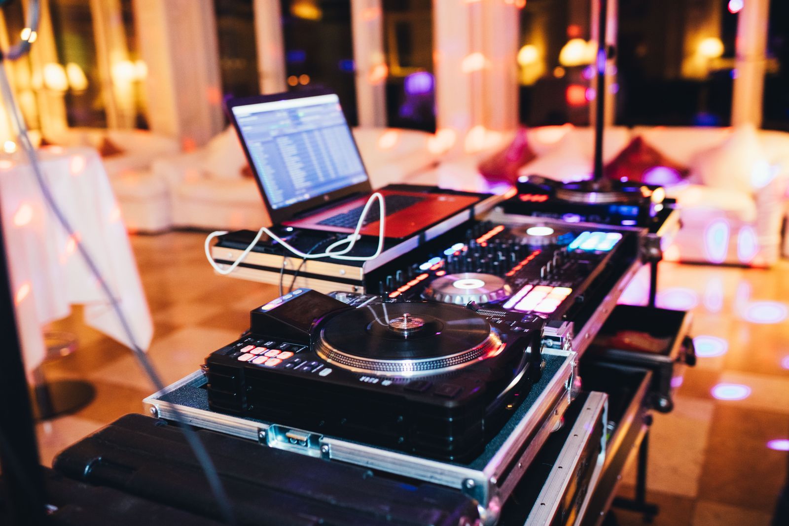 Cabina de DJ con reproductores y portátil en un salón de celebraciones