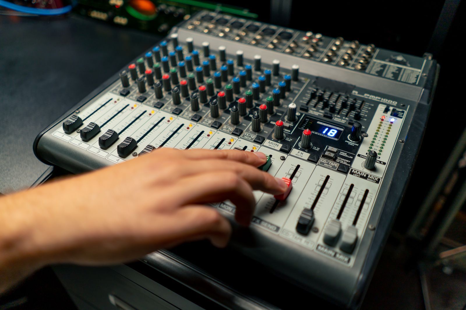 Manos de un técnico moviendo los faders de una mesa analógica