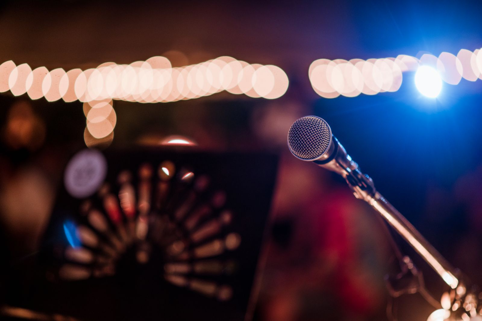 Micrófono en el escenario de una verbena, con guirnaldas de luces al fondo