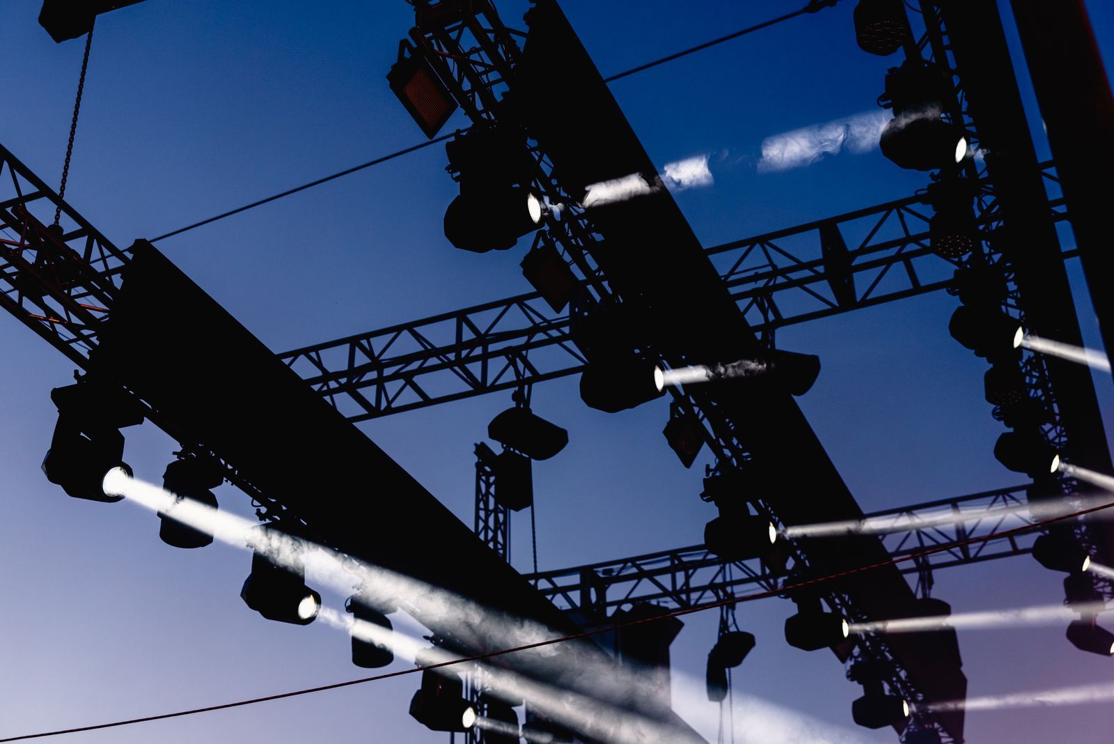 Focos colgados de un truss apuntando al cielo al anochecer